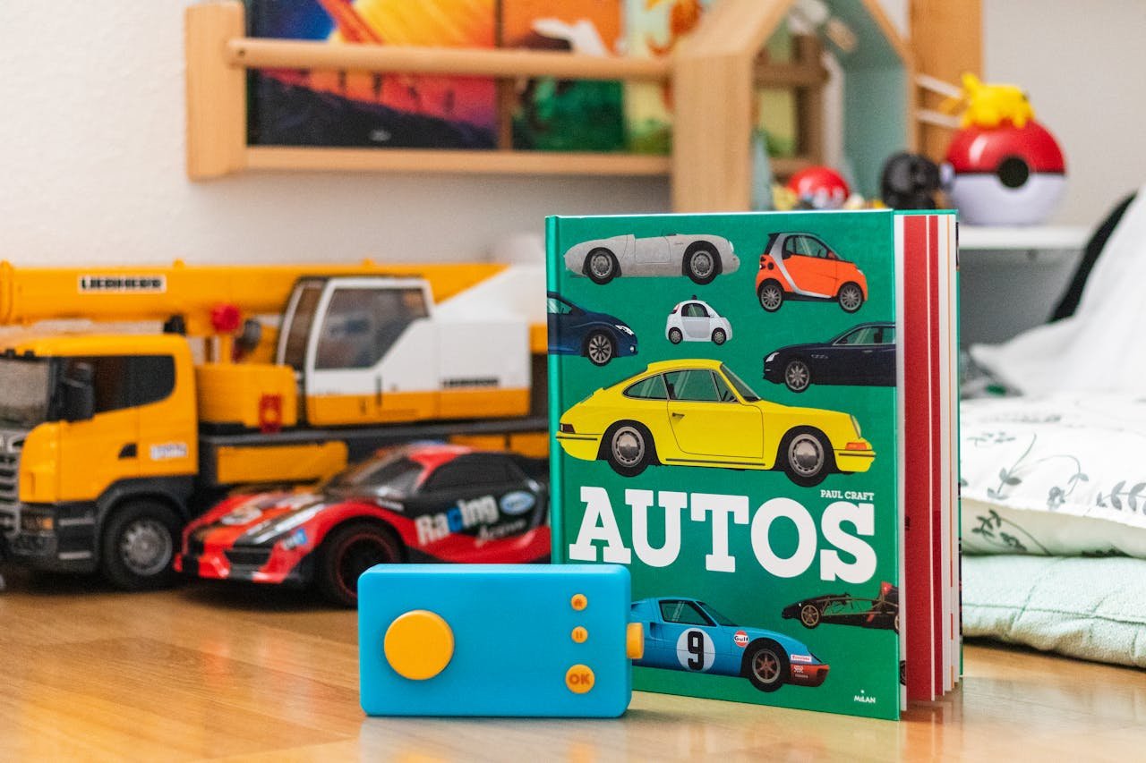 Menu Vibrant display of children's auto book and toy cars set on a wooden surface.