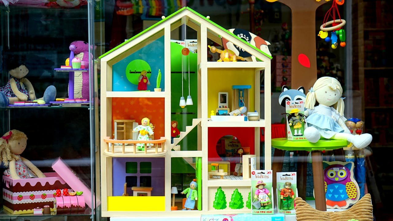A vibrant dollhouse and stuffed toys displayed in a toy store window, perfect for children