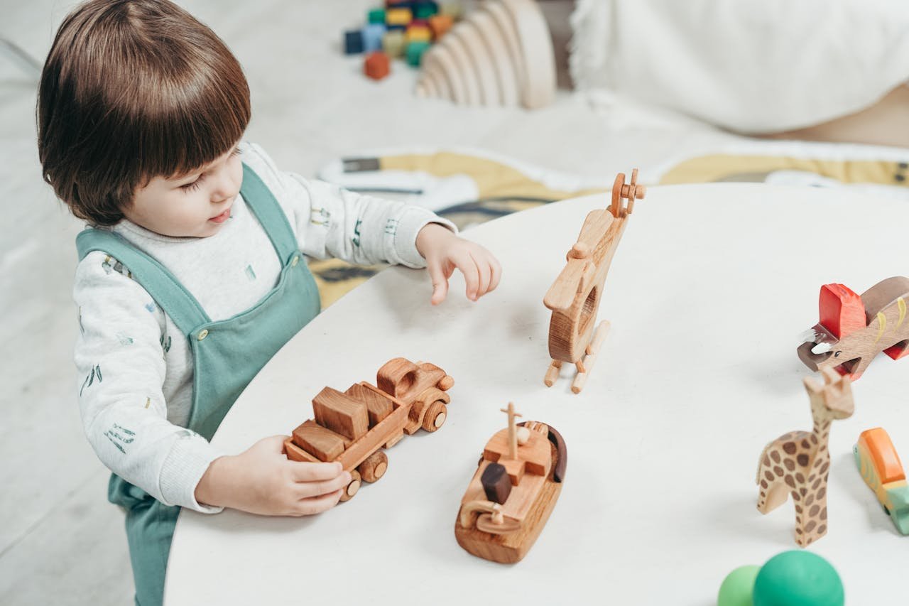 Menu A young child playing with wooden toys at a round table in a bright playroom.