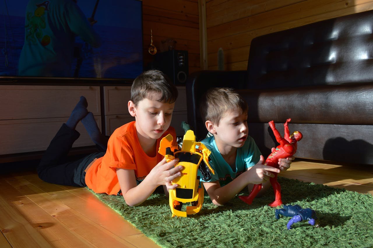 About Two boys enjoying playtime with toy cars and action figures on a sunny indoor rug.